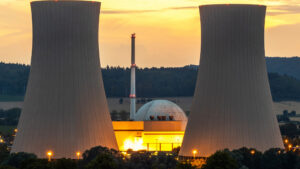 Nuclear power plant with two large cooling towers and concrete dome at sunset