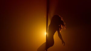 Woman silhouette practicing poledance in club.